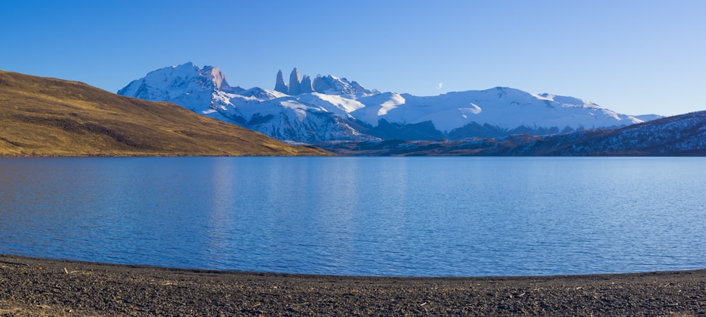 blue lake near brown and white mountains under blue sky during daytime