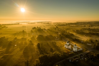 A serene landscape with a sunrise illuminating a peaceful church in the foreground.