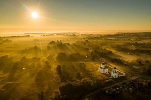 A serene landscape with a sunrise illuminating a peaceful church in the foreground.