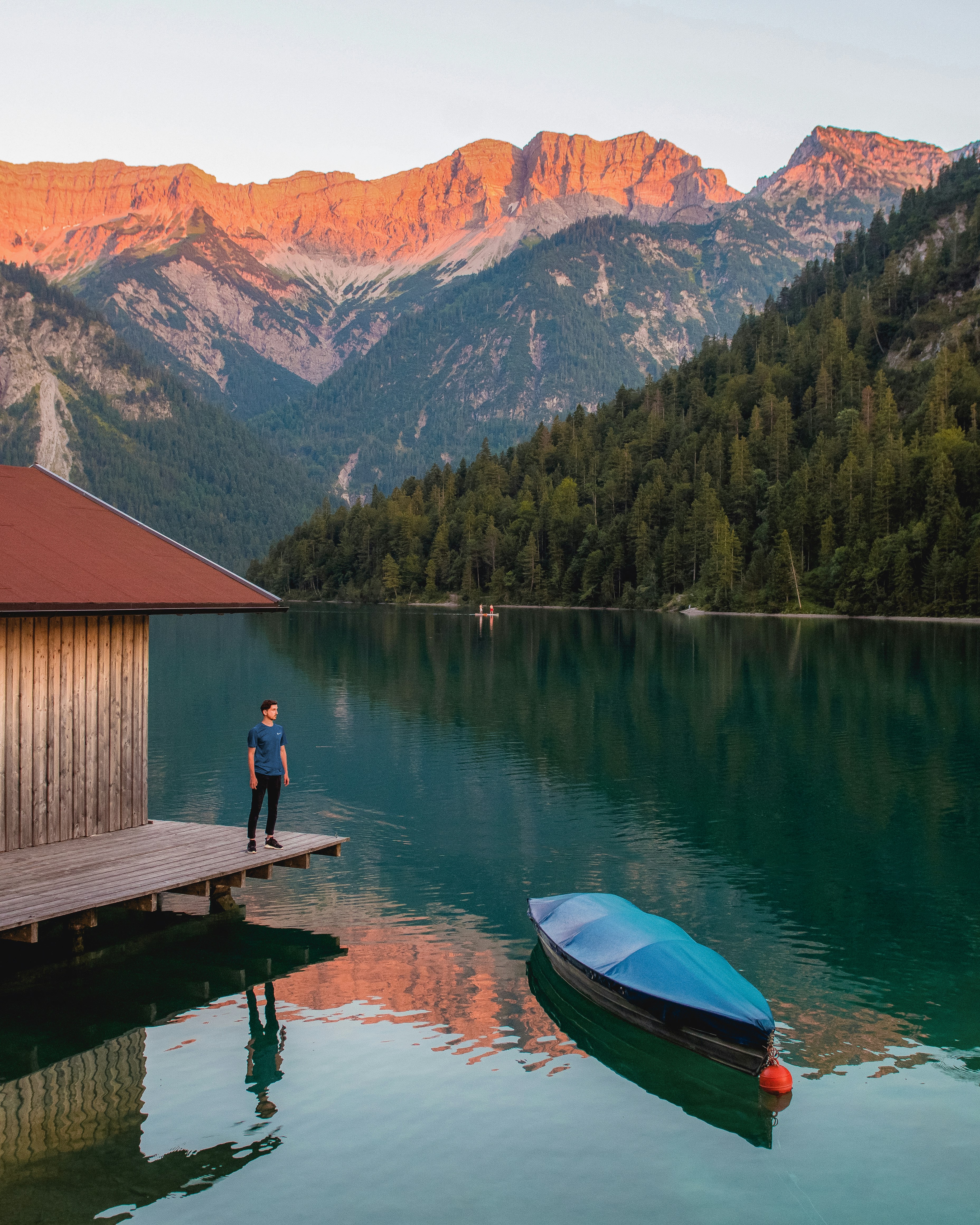 person in green jacket sitting on brown wooden dock during daytime