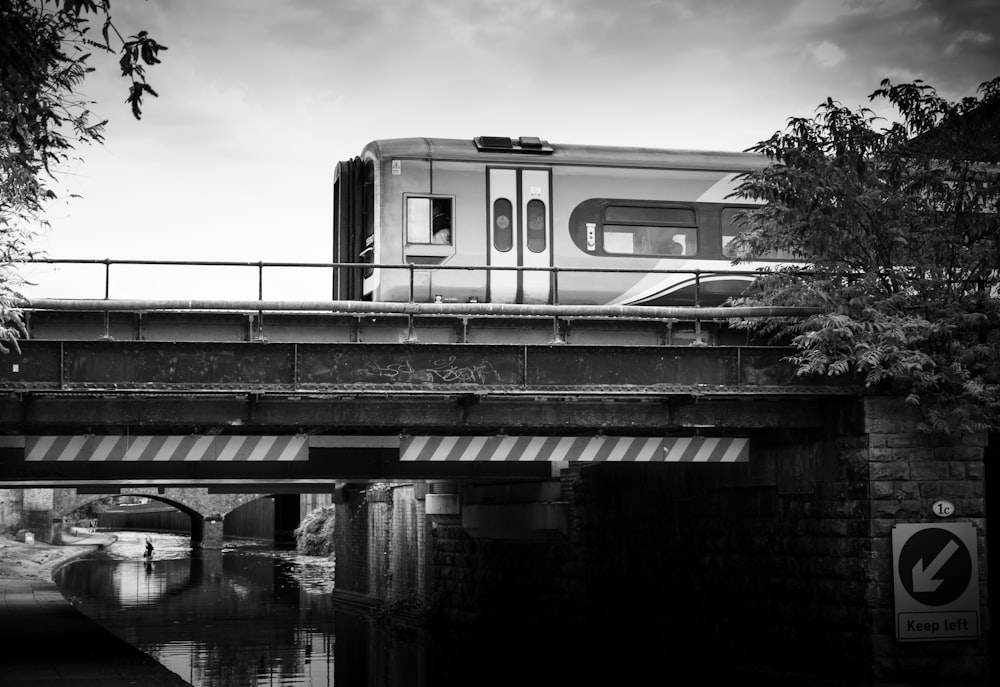 grayscale photo of a train on a bridge