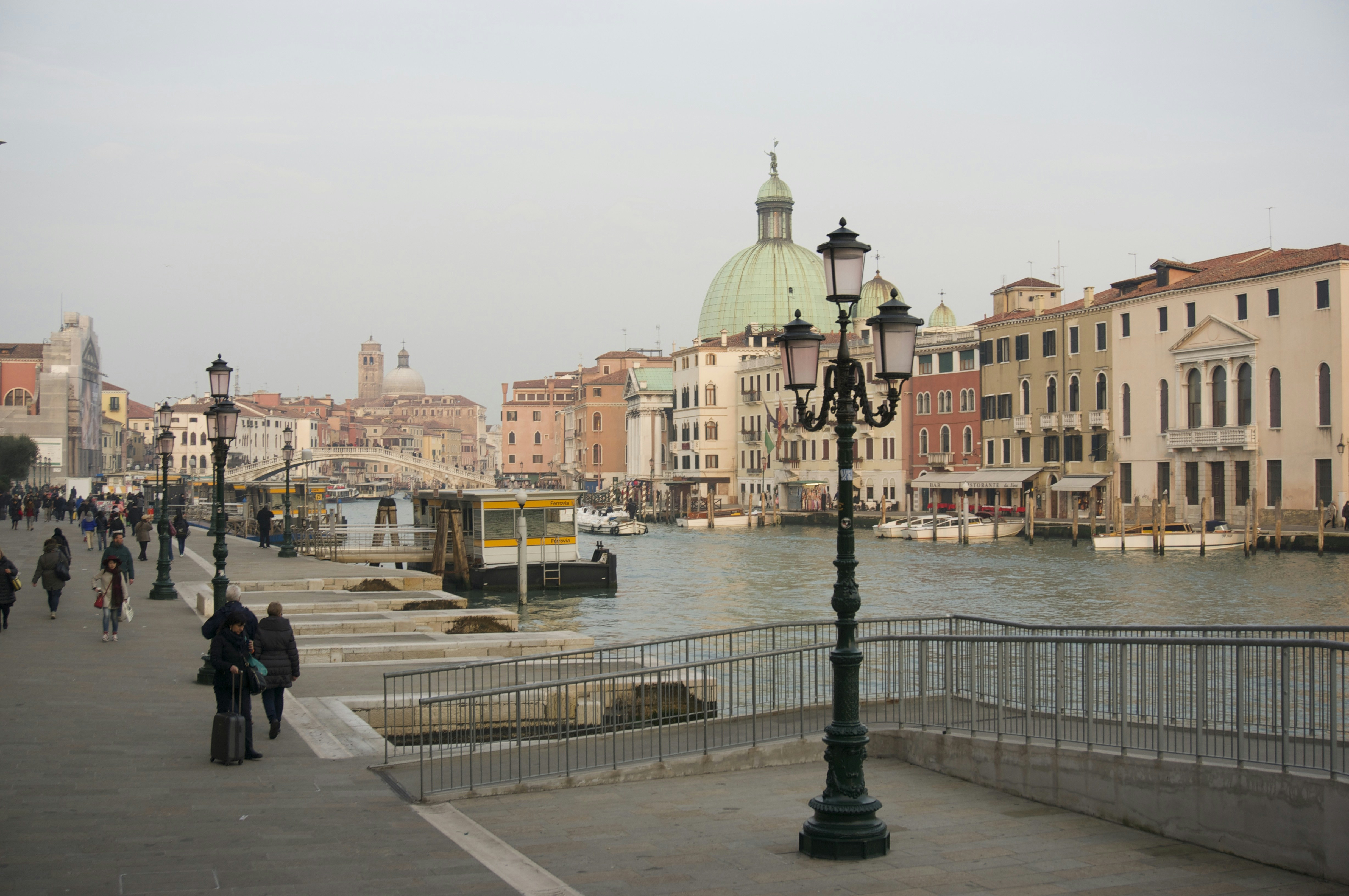 people walking on sidewalk near body of water during daytime
