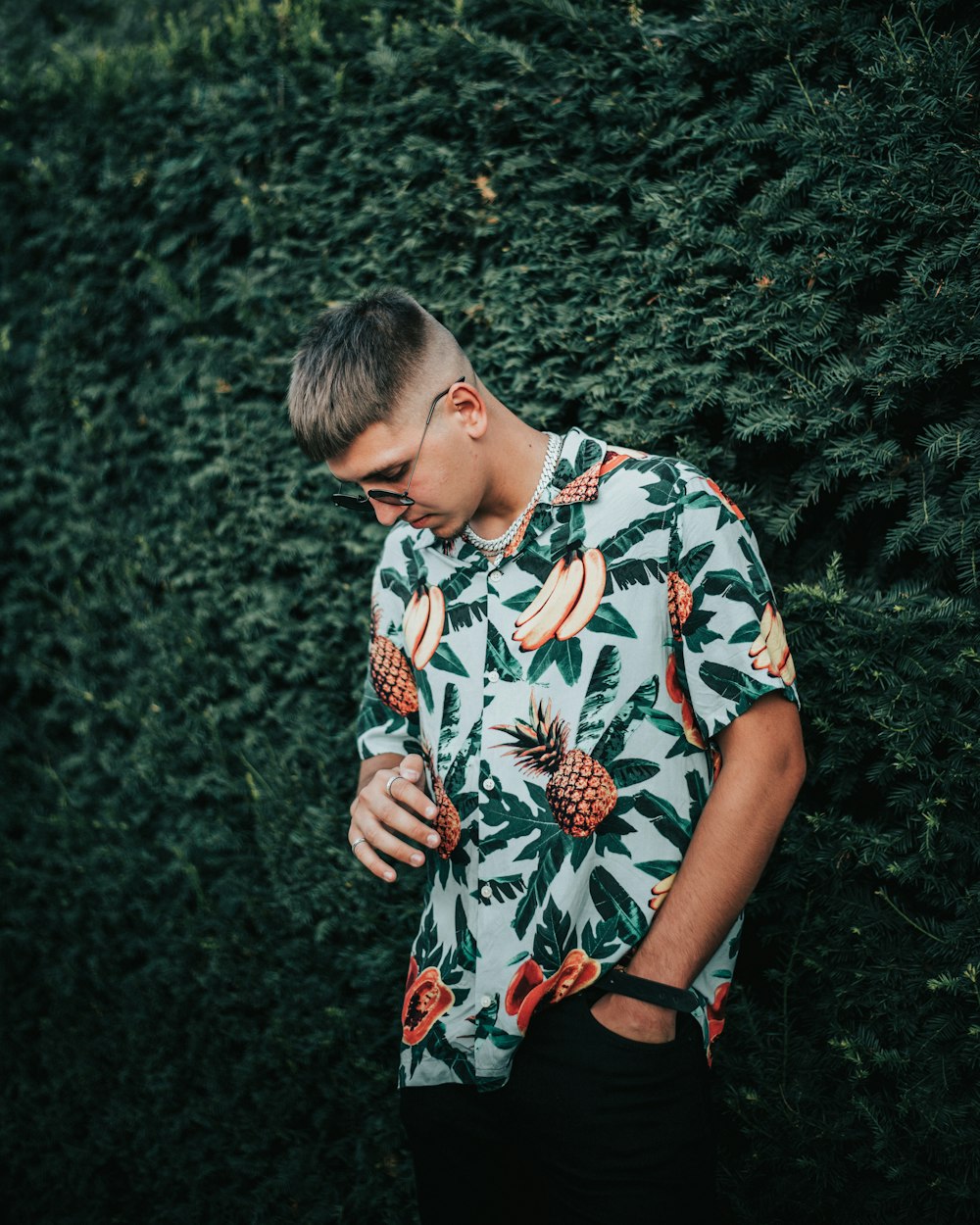 man in white blue and red floral crew neck t-shirt standing near green grass during