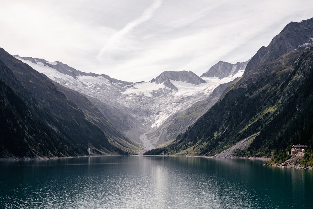 lake near mountains under white sky during daytime