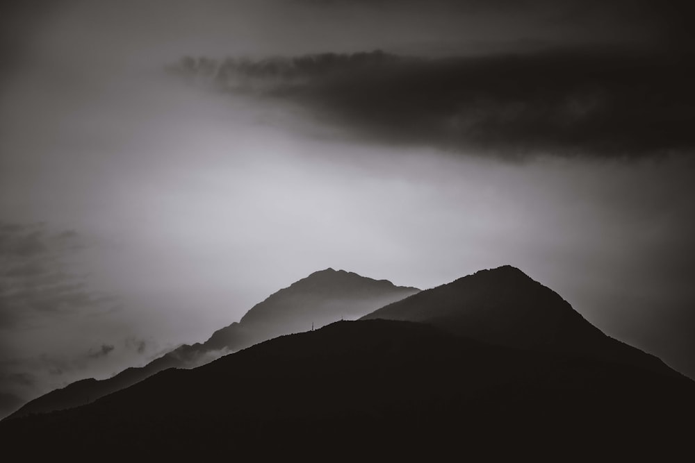 grayscale photo of mountains under cloudy sky