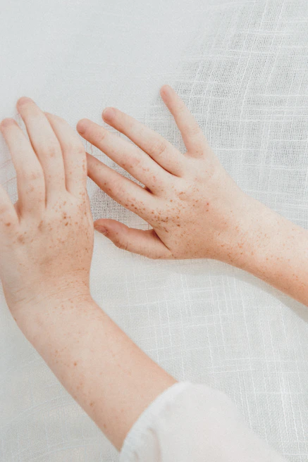 Close-up of hands gently touching the textured fabric of a vibrant clay heart jacket, highlighting the craftsmanship.