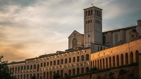 Brown concrete building under white clouds during daytime — Assisi, Italy