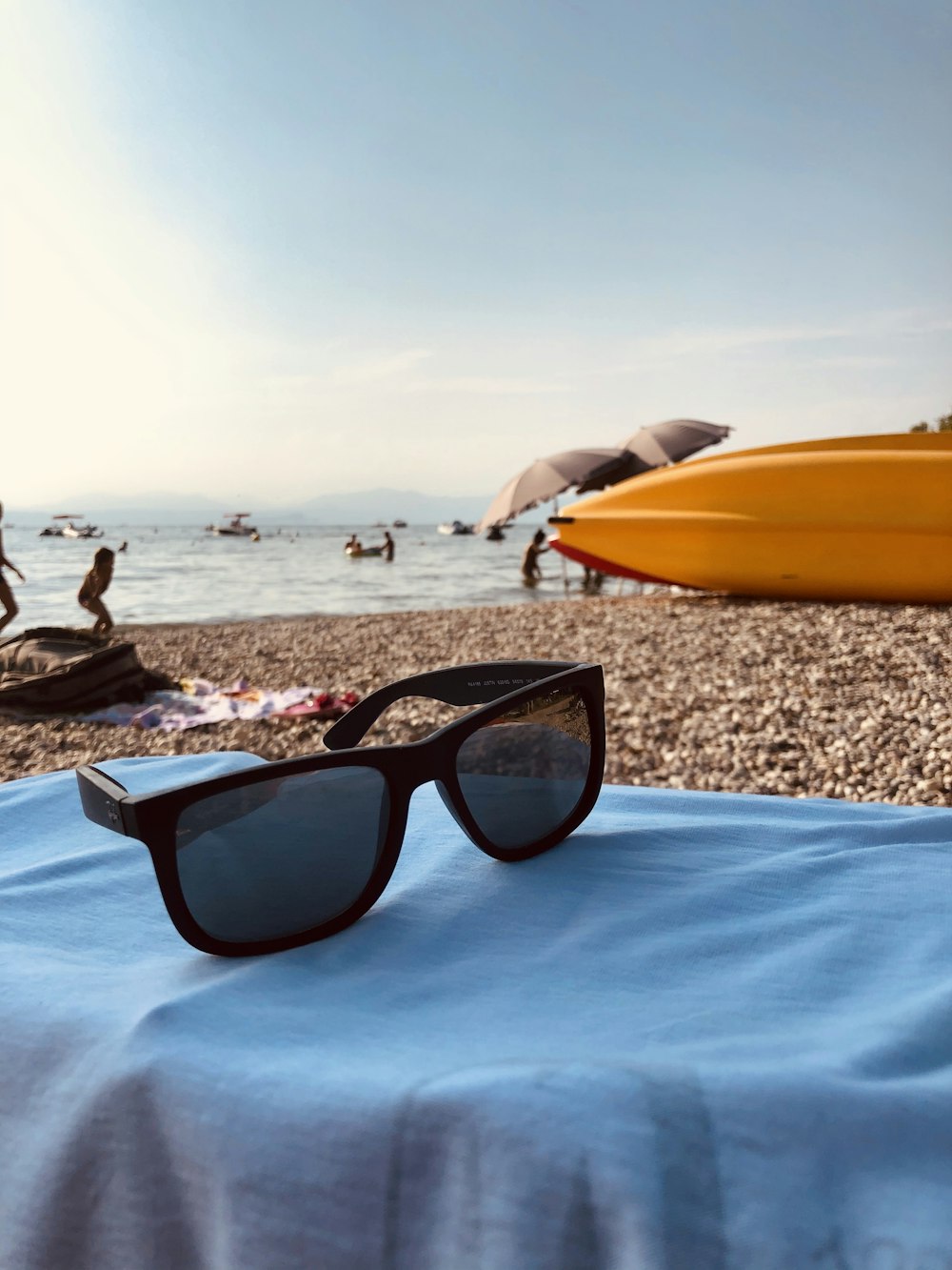 black framed sunglasses on brown sand near body of water during daytime