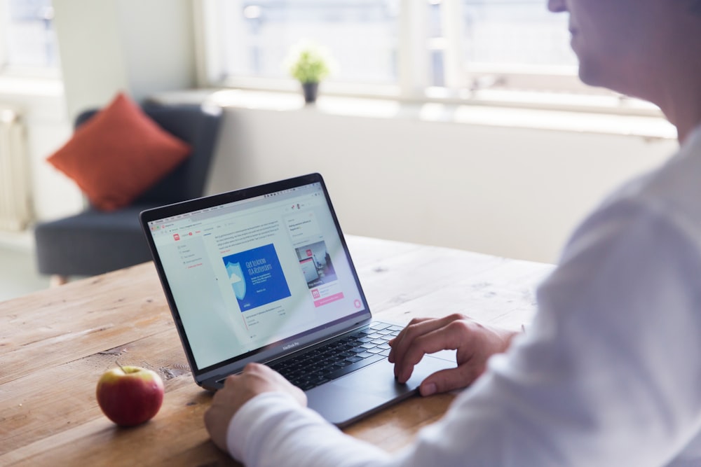 person using macbook pro on table