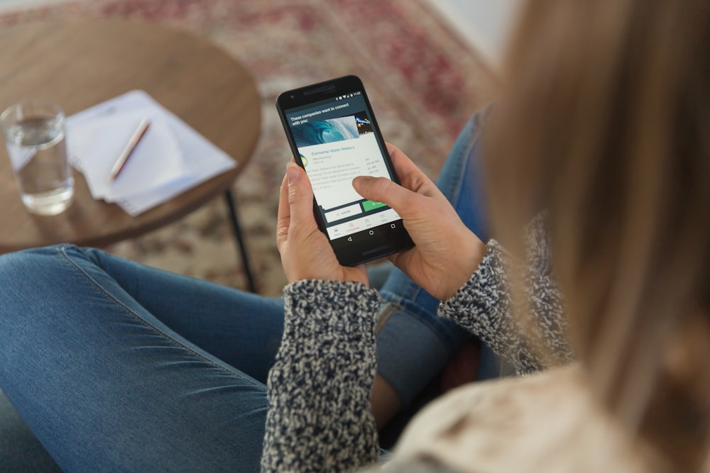 Persona sosteniendo un teléfono inteligente Android negro
