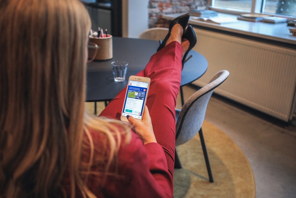 woman in red jacket holding white smartphone