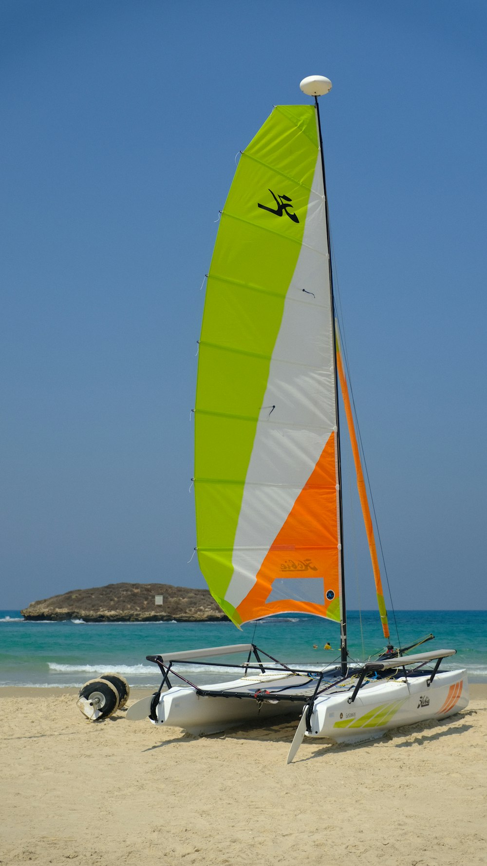 yellow green and red striped sail boat on sea during daytime