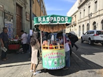 Happy customers enjoying colorful raspados under a bright, cheerful canopy at Raspados El Zalate.