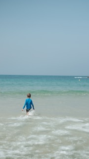 man in blue shirt surfing on sea during daytime
