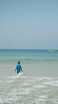 man in blue shirt surfing on sea during daytime