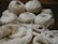 Several skeins of cream-colored yarn sit in the background, while knitting needles hold a partly-knitted fabric in the foreground. The scene suggests a cozy, crafty atmosphere.