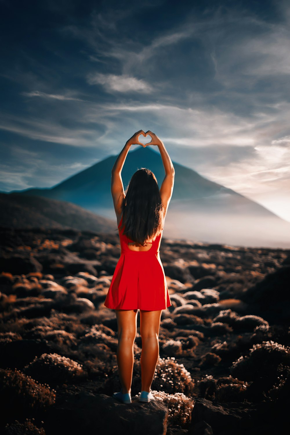 woman in red dress standing on rocky ground during daytime