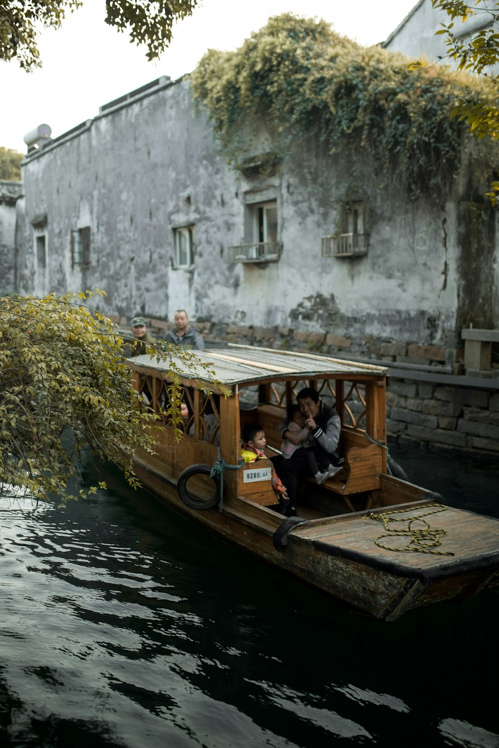 man in black jacket sitting on black wooden boat on river during daytime