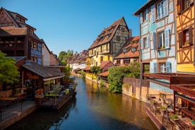 brown and white concrete buildings beside river under blue sky during daytime