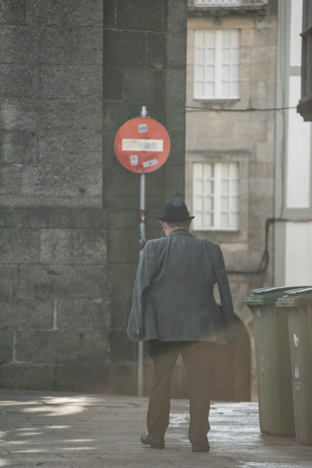 man in black coat standing near red stop sign