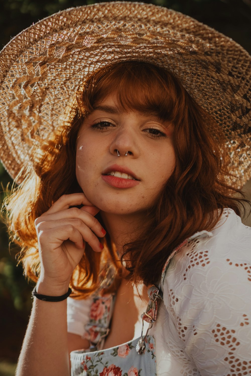 menina na camisa floral branca que veste o chapéu marrom do sol