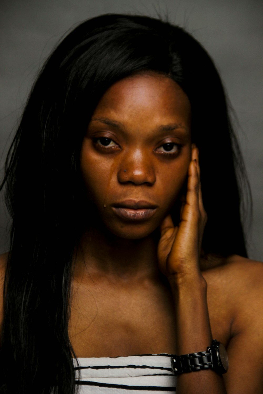 woman with black hair holding her face