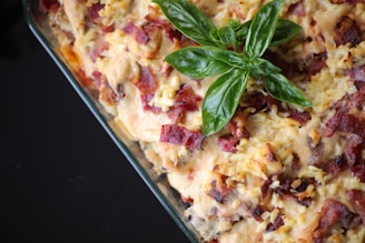 Close-up of a creamy cowboy chicken casserole topped with crispy bacon and melted cheese in a rustic baking dish.