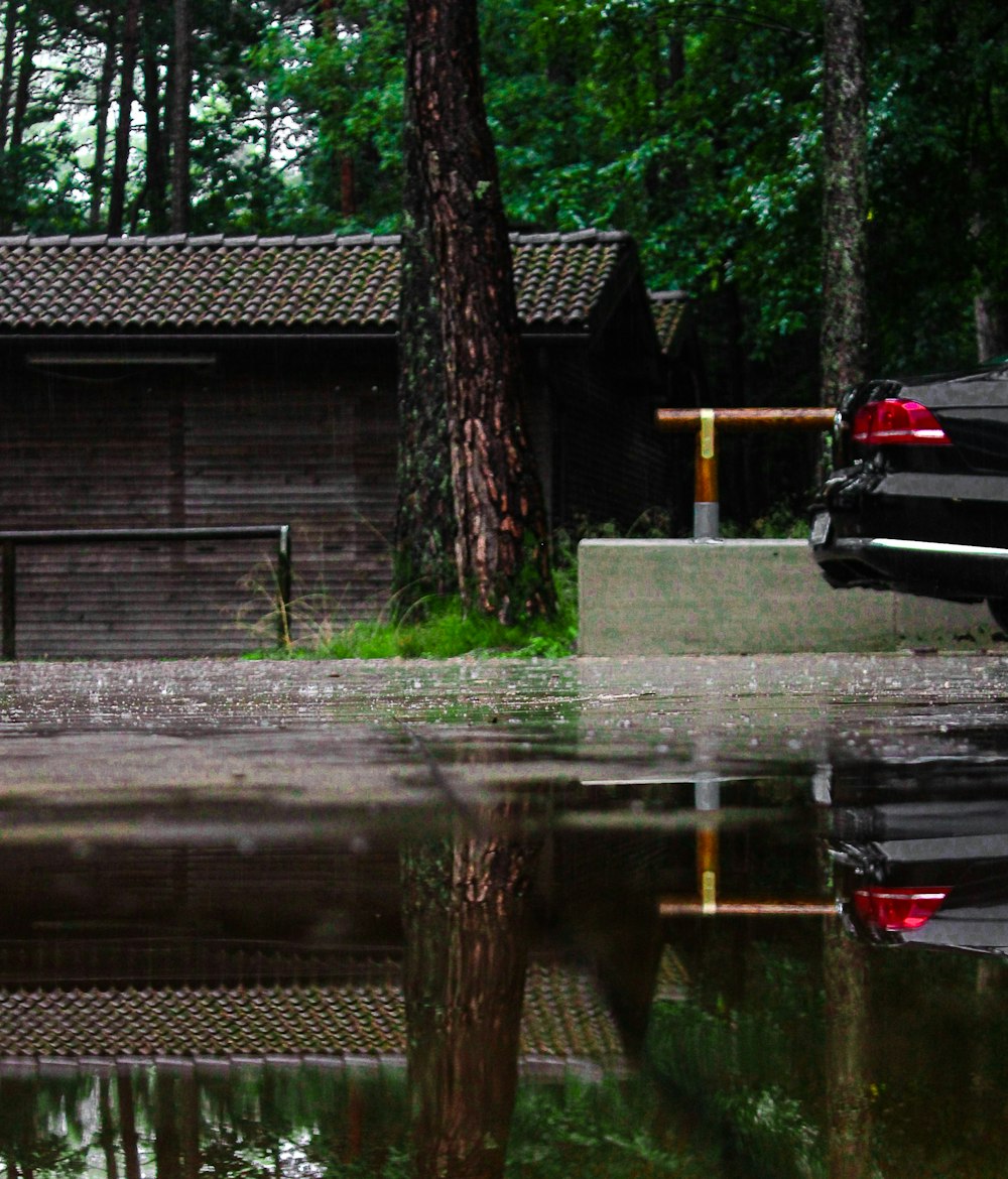 black car parked beside brown wooden house