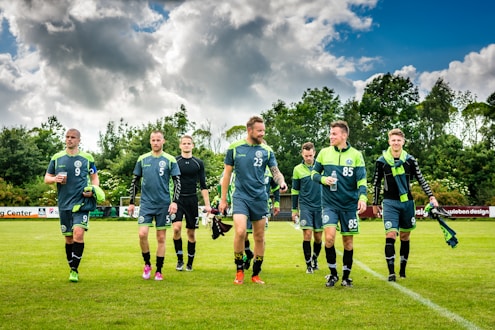 group of men in green soccer jersey shirt on green grass field