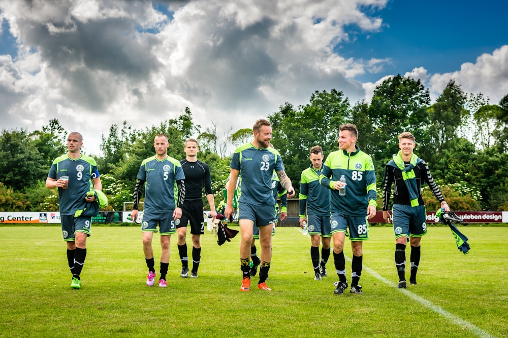 Grupo de hombres en camiseta de fútbol verde en campo de hierba verde