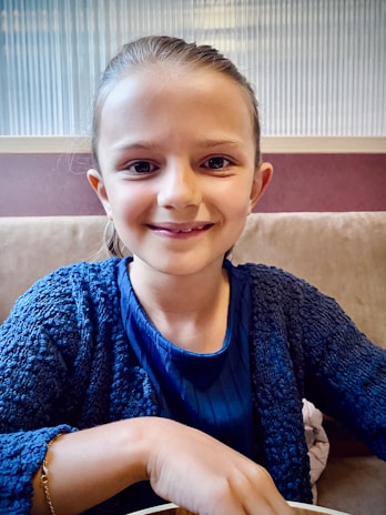 A smiling boy dressed in comfortable kids' wear sitting on a cozy sofa.