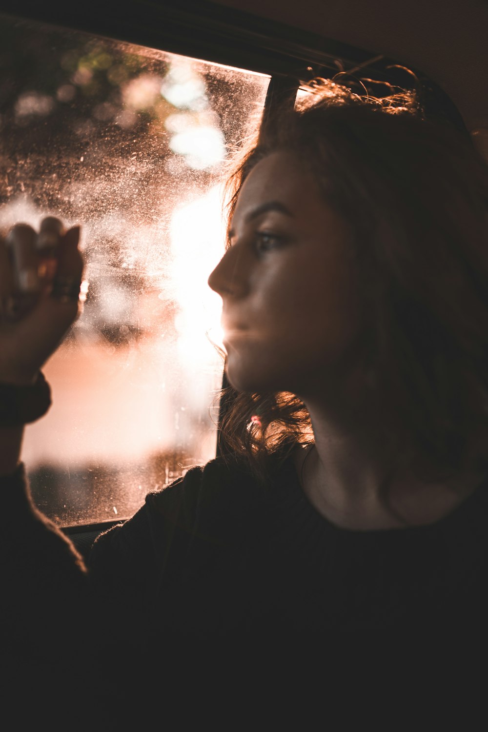 woman in black shirt holding her chin