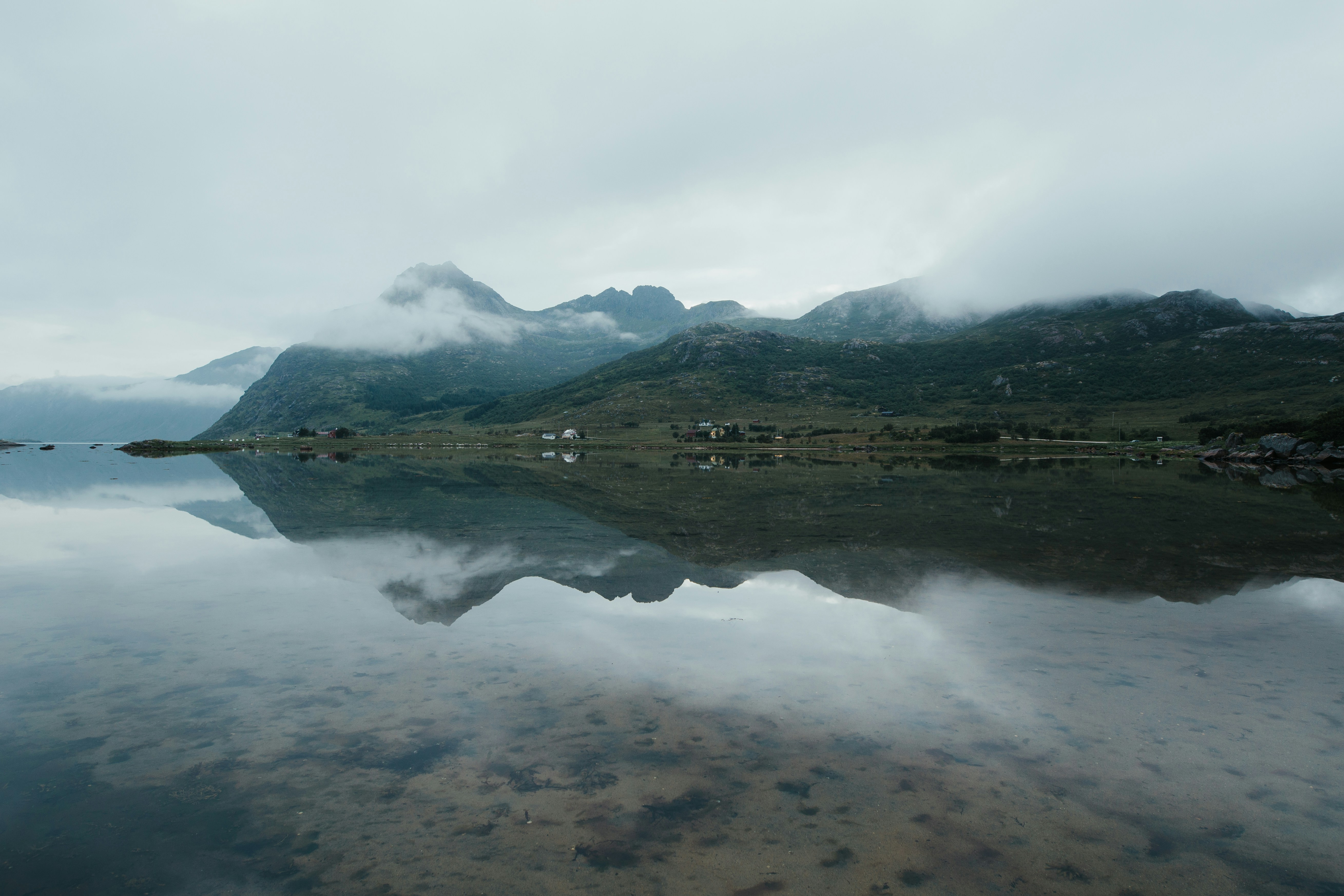 Montagne verte à côté d’un plan d’eau sous des nuages blancs pendant la journée