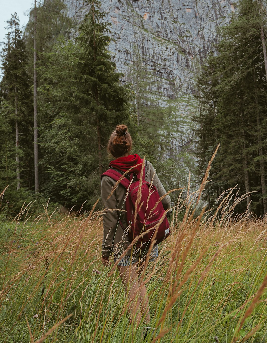 woman in brown coat standing on green grass field during daytime