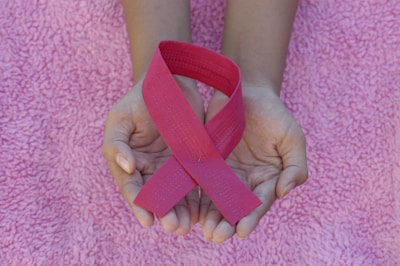 A close-up of hands holding pink ribbons.