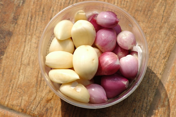 Close-up of vibrant dehydrated onion flakes and garlic granules arranged on rustic wooden surface.