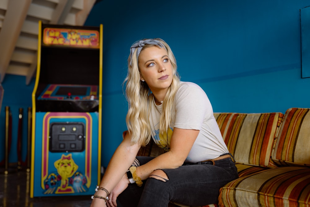 woman in white crew neck t-shirt and black denim jeans sitting on brown wooden armchair