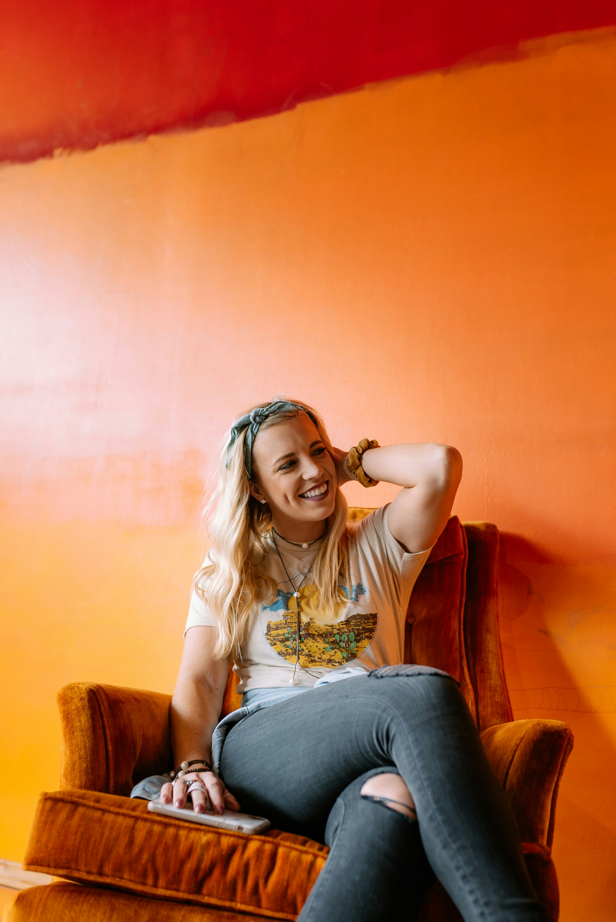 woman in white shirt and blue denim jeans sitting on brown sofa