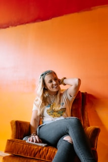 woman in white shirt and blue denim jeans sitting on brown sofa