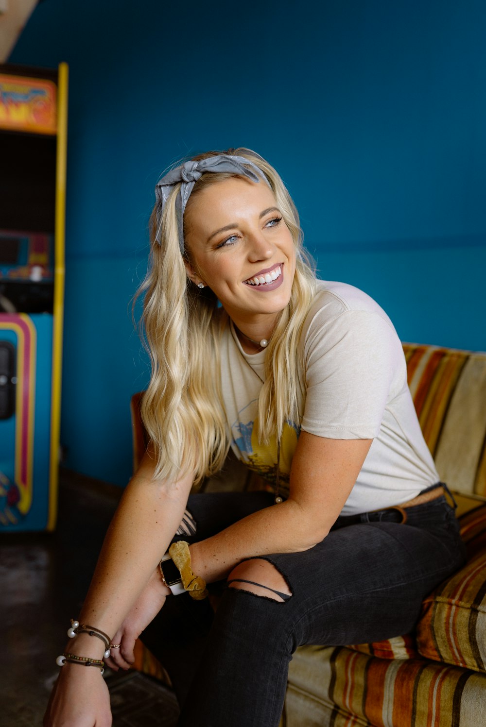 smiling woman in white crew neck t-shirt and blue denim jeans sitting on brown wooden