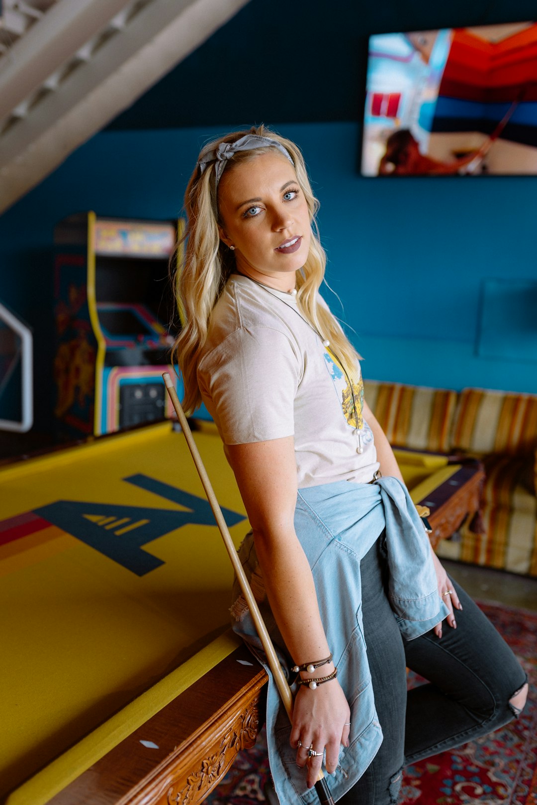 woman in yellow shirt and blue denim jeans sitting on yellow metal bar