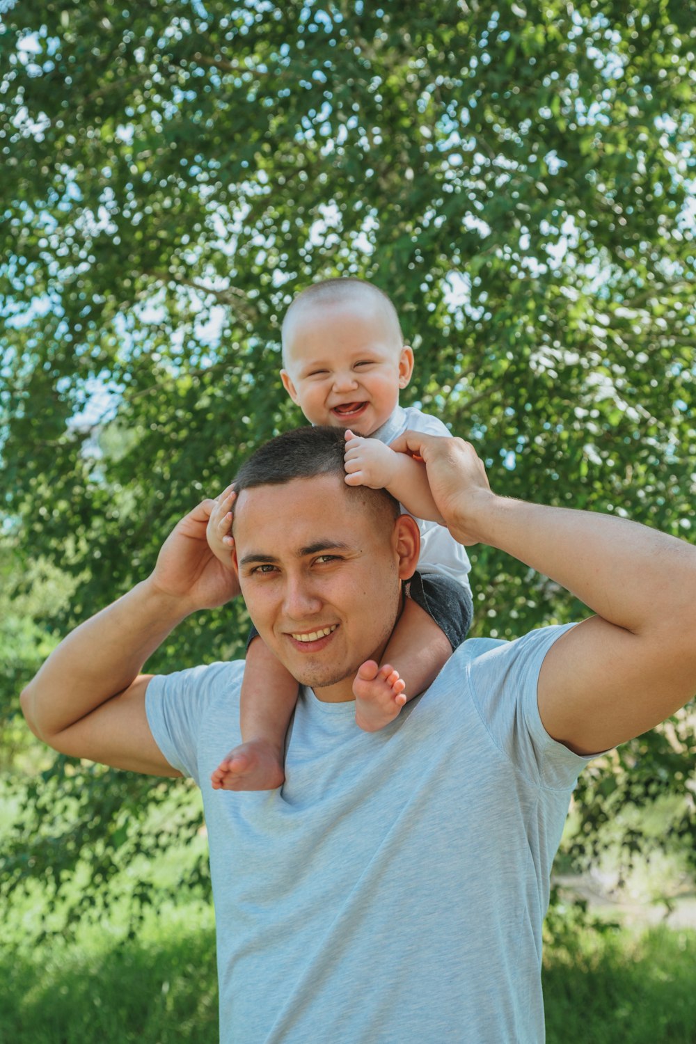 woman in gray crew neck t-shirt carrying baby during daytime