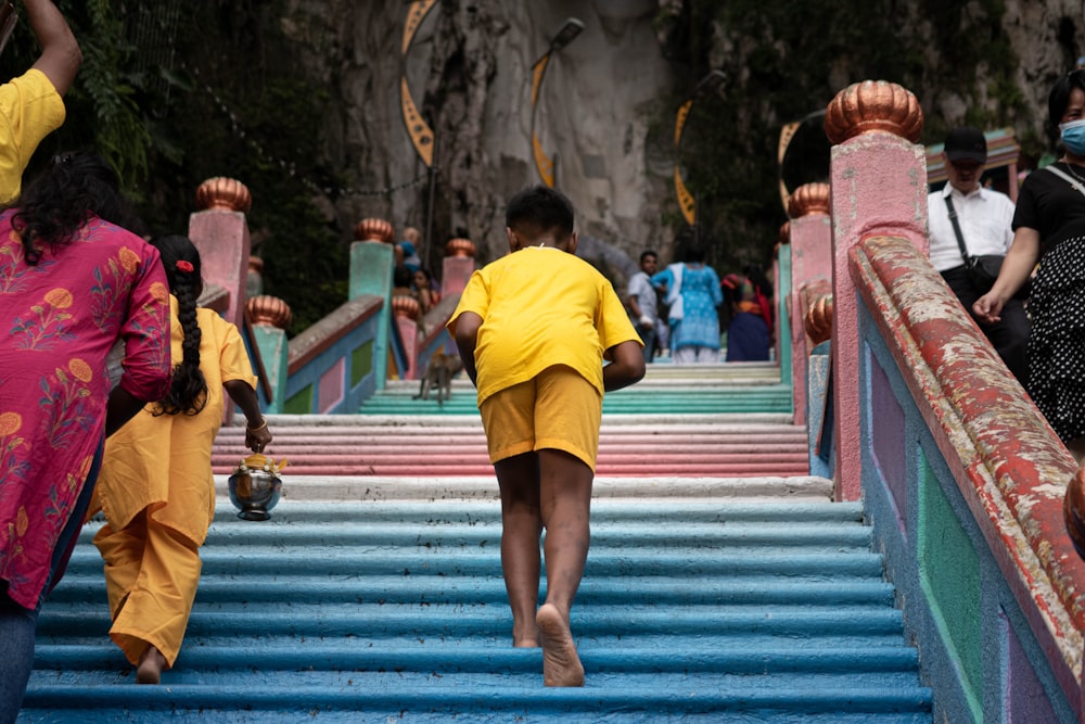 woman in yellow shirt and black skirt walking on blue stairs