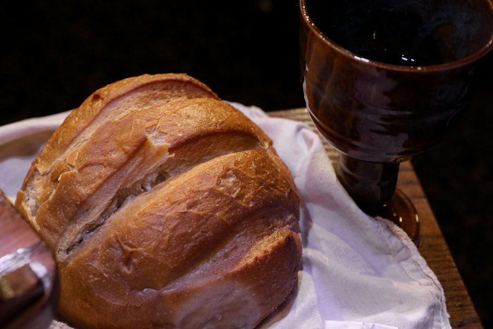 Brot auf weißem Seidenpapier neben schwarzem Keramikbecher