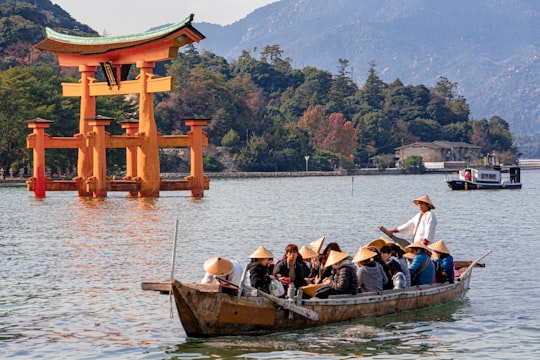 people riding boat on lake during daytime in Itsukushima Japan