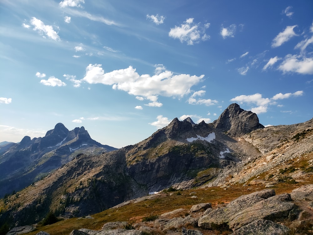 brown and green mountains under white clouds and blue sky during daytime