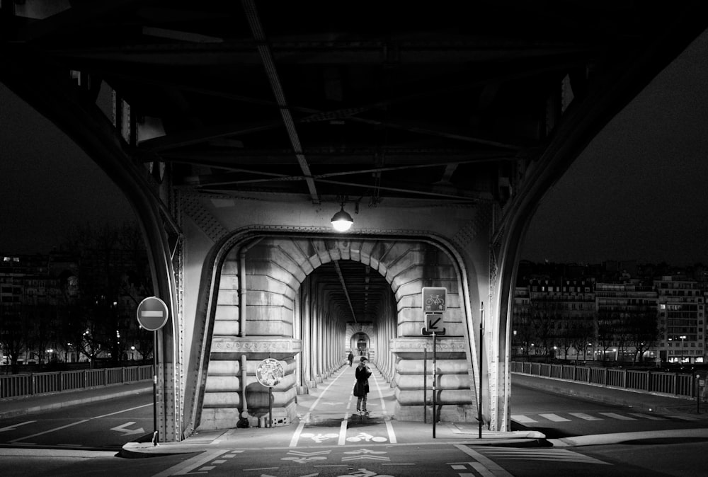 grayscale photo of woman walking on sidewalk