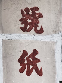 Two large, bold red Chinese characters are painted on a worn concrete surface. The texture shows noticeable weathering and scratches.