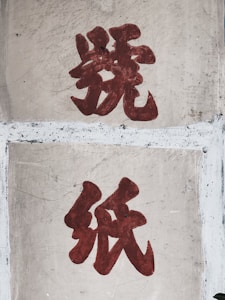 Two large, bold red Chinese characters are painted on a worn concrete surface. The texture shows noticeable weathering and scratches.