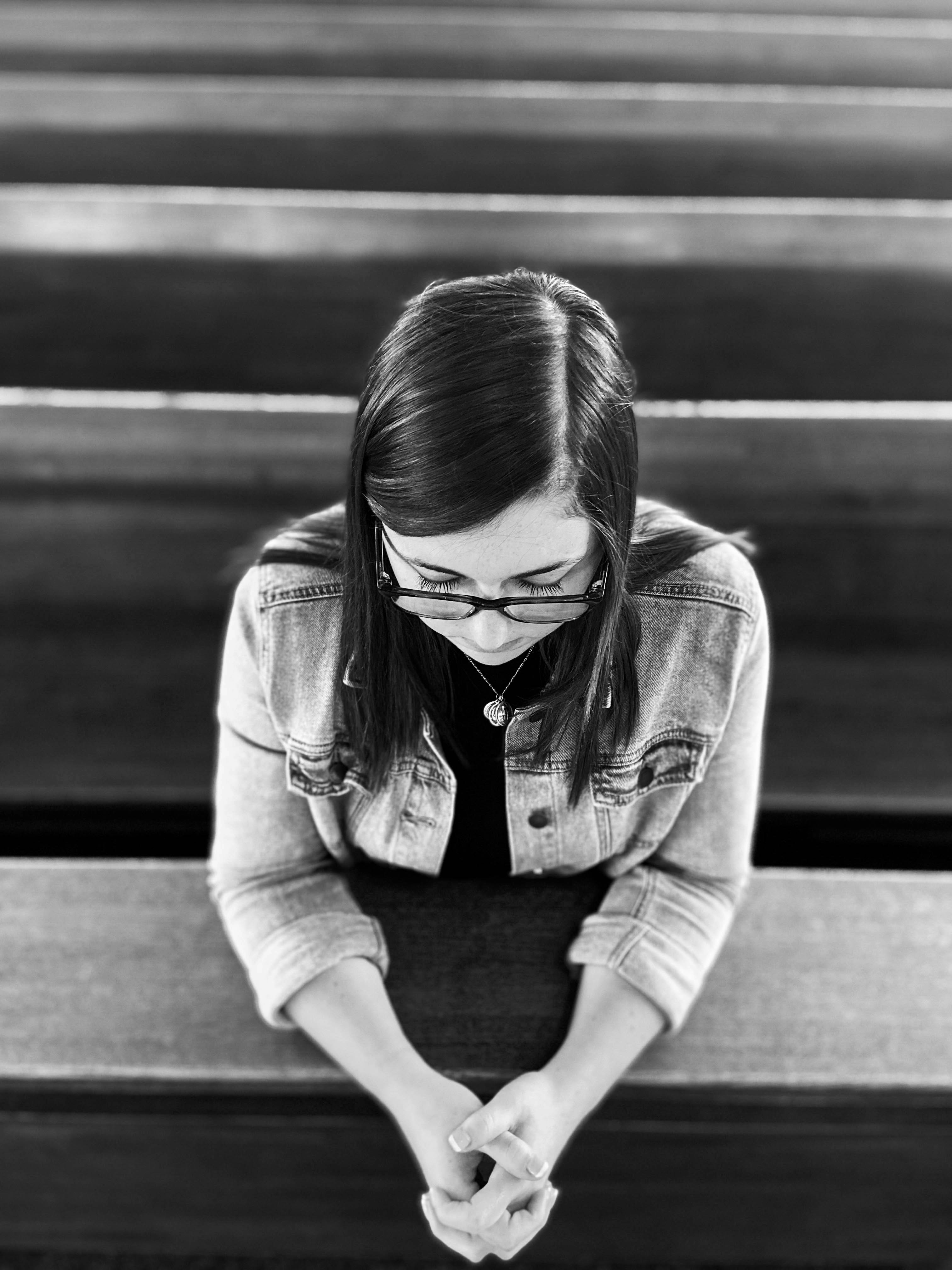 Foto en escala de grises de una mujer con chaqueta vaquera y gafas
